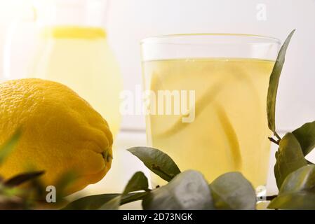 Glas gefüllt mit frisch gepresstem Zitronensaft mit Zitronenstück isoliert weiß. Vorderansicht. Horizontale Zusammensetzung. Stockfoto