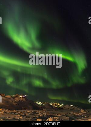 Nordlichter über der Stadt und gefrorene Disko Bay. Stadt Ilulissat am Ufer der Disko Bay in Westgrönland, Zentrum für Tourismus, Verwaltung und Öko Stockfoto