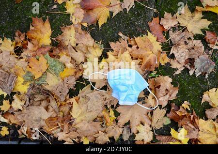 Weggeworfene Gesichtsmasken auf dem Boden unter herbstbraunen Blättern In london im Vereinigten Königreich kovid 19 Pandemie 2020 Stockfoto