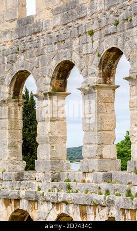 Details von Bögen und Säulen in den Außenwänden des ikonischen antiken römischen Amphitheaters in Pula, Istrien, Kroatien, eine führende Touristenattraktion Stockfoto