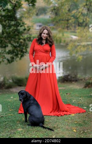Frau in einem roten Kleid für Mutterschaftsfotos Stockfoto