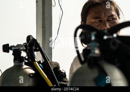 Calventuras Islands, Ngwesaung, Myanmar, 29. Dezember 2019: Portrait eines lokalen burmesischen Tauchlehrers hinter zwei Metall-Sauerstofftanks Ausrüstung Stockfoto