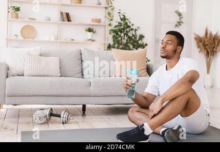 Mann Hält Flasche Wasser Trinken Während Des Trainings Zu Hause Stockfoto