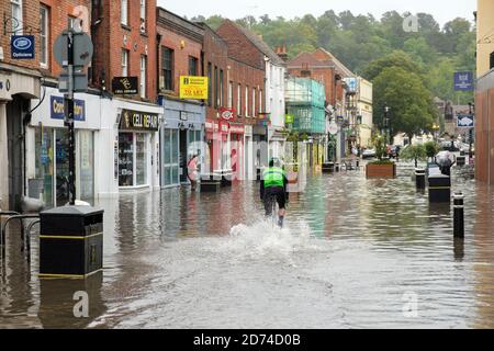 Winchester, England, UK 27/08/2020 EIN Radfahrer, der durch Hochwasser auf der High Street in Winchester nach schweren Regenfällen durch Sturm Francis. Stockfoto