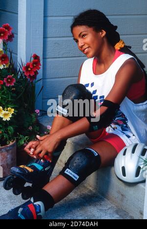 Attraktive Mixed-Race-junge FrauenLeces up her Rollerblades, 1995, USA Stockfoto