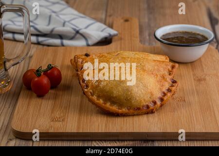 Argentinische Empanadas mit einem Glas Bier über einem hölzernen Tabelle Stockfoto