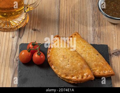 Argentinier Fleisch Empanadas mit einem Glas Bier über ein Holztisch Stockfoto