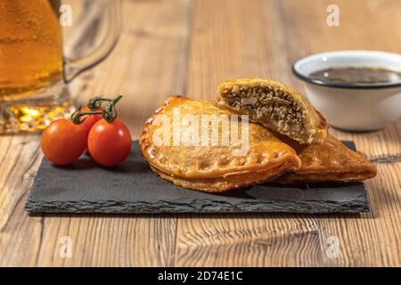 Argentinier Fleisch Empanadas mit einem Glas Bier über ein Holztisch Stockfoto