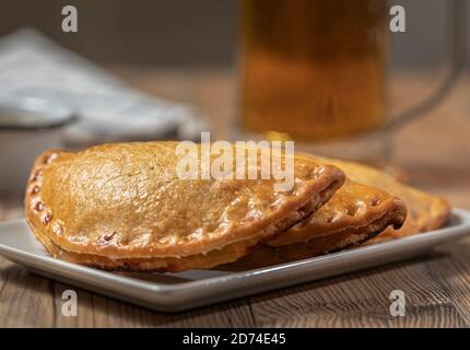 Argentinier Fleisch Empanadas mit einem Glas Bier über ein Holztisch Stockfoto