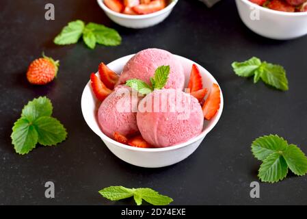 Erdbeereis in Schale auf dunklem Steinhintergrund. Kalter Sommerdessert Stockfoto