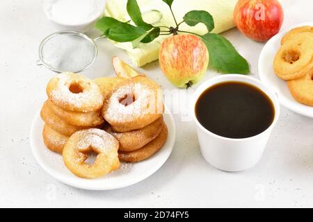 Apfelringe auf weißem Teller, Tasse schwarzen Kaffee auf weißem Stein Hintergrund Stockfoto