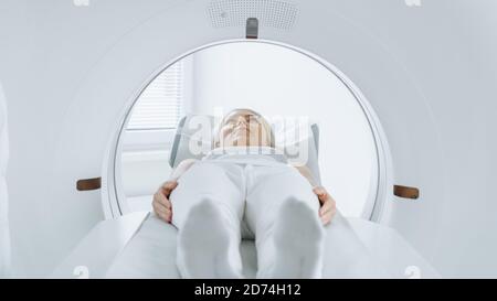 Nahaufnahme Porträt einer Patientin, die auf einem CT- oder MRT-Scan liegt, bewegt sich das Bett im Inneren des Geräts, während es Körper und Gehirn scannt. In Medizin Stockfoto