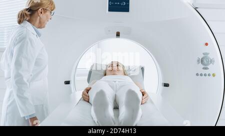 Im medizinischen Labor wird eine Patientin, die auf einem CT- oder MRI-Scan-Bett liegt, unter Aufsicht eines professionellen Radiologen einem Scan-Verfahren unterziehen. Stockfoto