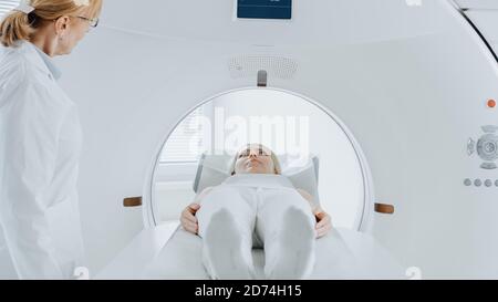 Nahaufnahme Porträt einer Patientin, die auf einem CT- oder MRT-Scan liegt, bewegt sich das Bett im Inneren des Geräts, während es Körper und Gehirn scannt. In Medizin Stockfoto