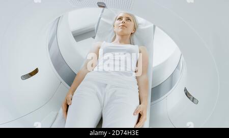 Nahaufnahme Porträt einer Patientin, die auf einem CT- oder MRI-Scan liegt, Bett bewegt sich in der Maschine und scannt ihren Körper und ihr Gehirn. Im medizinischen Labor mit Stockfoto