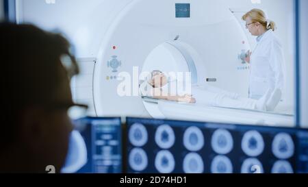 Im medizinischen Labor Patient durchläuft MRI oder CT-Scan-Prozess unter Aufsicht von Radiologen, im Kontrollraum Arzt Uhren Verfahren und Monitore Stockfoto