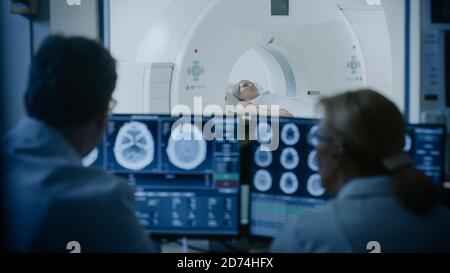 Im medizinischen Labor Patient durchläuft MRI oder CT-Scan-Prozess unter Aufsicht des Arztes und Radiologen im Kontrollraum, sie watche Verfahren und Stockfoto