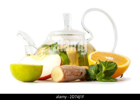 Isolierte transparente Teekanne aus Glas mit Tee aus Ingwerwurzel, Limette, Orange, Apfel, Minze Stockfoto