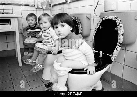 15. November 1984, Sachsen, Wildenhain: Im November 1984 sitzen Kinder nebeneinander auf der Toilette in einem Dorfkindergarten in Wildenhain (bei Eilenburg). Genaues Datum der Aufnahme nicht bekannt. Foto: Volkmar Heinz/dpa-Zentralbild/ZB Stockfoto