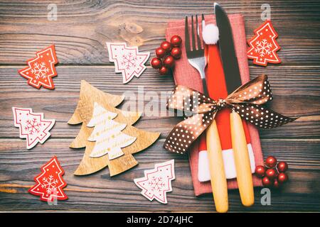 Blick von oben auf die Gabel und Messer, mit Band gebunden auf Serviette auf Holz- Hintergrund. Nahaufnahme von Weihnachtsschmuck und Tannenbaum. Happy Holiday conc Stockfoto