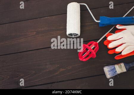 Gegenstände und Werkzeuge des professionellen Malers auf Holzhintergrund. Maler und Dekorateur Arbeitstisch, Schneebesen zum Mischen von Farbe, Handschuhe, Malerrolle und pa Stockfoto