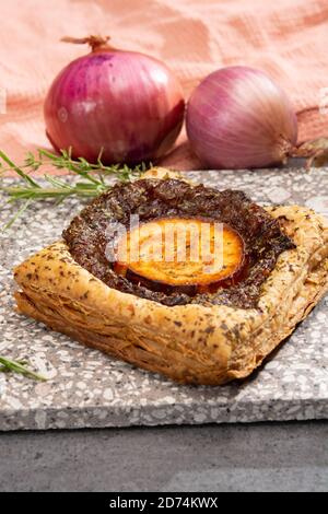 Frisch gebackene Blättertörtchen mit karamellisierten Zwiebeln und Ziegenkäse Nahaufnahme Stockfoto