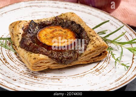 Frisch gebackene Blättertörtchen mit karamellisierten Zwiebeln und Ziegenkäse Nahaufnahme Stockfoto