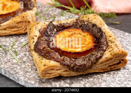 Frisch gebackene Blättertörtchen mit karamellisierten Zwiebeln und Ziegenkäse Nahaufnahme Stockfoto