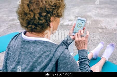 Rückansicht der älteren Frau mit dem Smartphone Stockfoto
