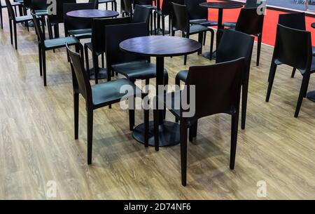 Moderner schwarzer Stuhl und Kreis Holztisch Set für Treffen zwischen Verkäufer und Kunde im Automobil-Showroom. Stockfoto