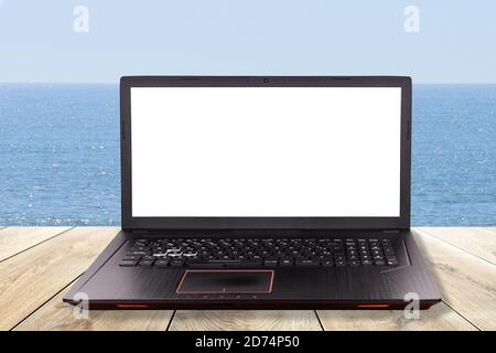 Schwarzer Laptop über einem Tisch am Strand als Konzept für Telearbeit, Telearbeit, Telearbeit Stockfoto
