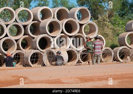 Sihanoukville, Kambodscha - 30. Dezember 2018 : Blick auf eine kambodschanische Straßenbaustelle mit Arbeitern auf der Straße und vielen Entwässerungs-Betonrohren Stockfoto