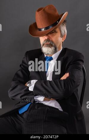 Ein schlafender Mann in einem Anzug mit Krawatte lehnte sich Zurück in seinem Stuhl und bedeckte sich mit einem Cowboy hut Stockfoto