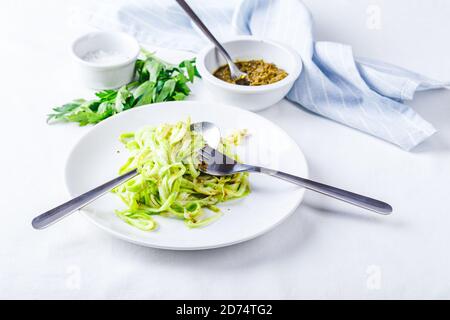 Gesunde Zucchini-Noddles mit Pesto auf weißem Hintergrund Stockfoto