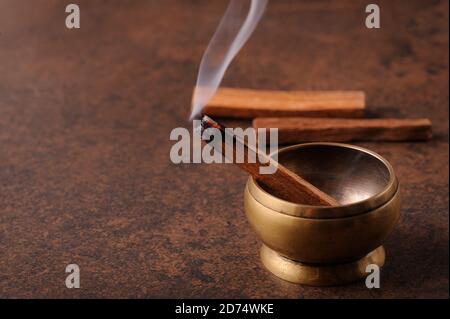 Aromatischer Stab von palo santo auf dunklem Hintergrund. Heiliges heiliges Baumstäbchen, brennend mit Duftrauch.Räuchern von Kräuterräuchern. Heilung, Meditation, Entspannung Stockfoto