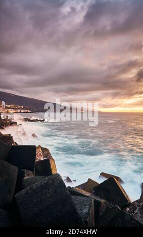 Einen malerischen Sonnenuntergang mit Wellen gegen die Felsen, Puerto de la Cruz, Teneriffa, Spanien. Stockfoto