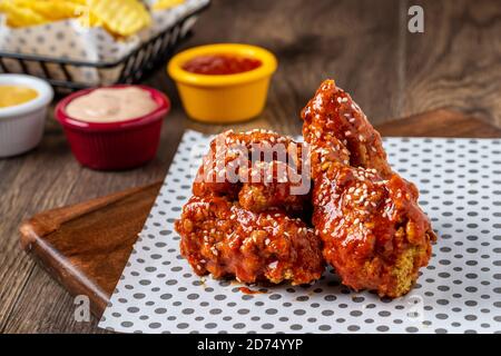 Gebackene Hähnchenflügel mit Sesam und Sauce auf Holzgrund Stockfoto