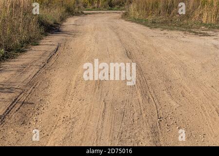 Staubige trockene Feldstraße mit wilden Grasdickicht auf seiner Seiten Stockfoto