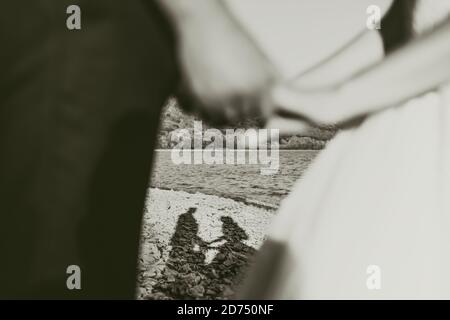 Der Bräutigam und die Braut halten die Hände im Fokus Ihre Schatten Silhouetten auf den Steinen Stockfoto