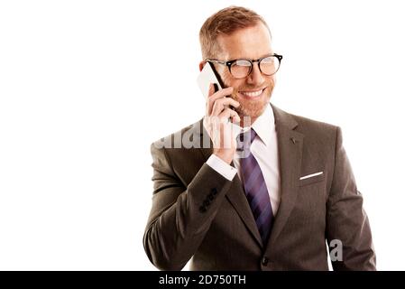 Glücklicher Geschäftsmann mittleren Alters, der Anzug trägt und Anrufe macht, während er auf einem isolierten weißen Background mit Kopieplatz steht. Stockfoto