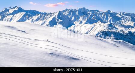 Single-Skifahrer geht bergab in Fresh Deep Snow in Front Des Alpenpanoramas Stockfoto