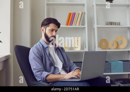 Porträt eines fokussierten Freiberuflers, der online am Computer arbeitet, der zu Hause im Wohnzimmer sitzt. Stockfoto