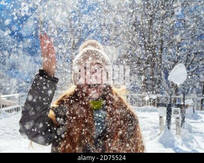 Schnee fällt von oben auf ein fröhliches Mädchen beleuchtet von Die Sonne Stockfoto