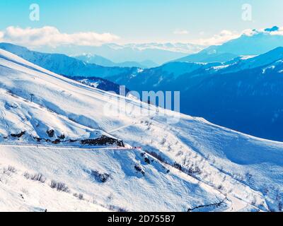 Verschneite Skipisten im Hintergrund der Bergketten und Blauer Himmel mit Wolken Stockfoto