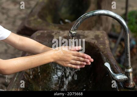 Hygienekonzept Händewaschen und Händewaschen im öffentlichen Park. Ein Junge wäscht seine Hände mit Seife im Holzbecken. Stockfoto