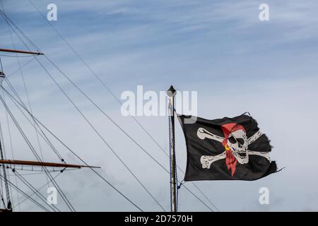 Ein fröhlicher roger oder Totenkopf und Kreuzknochen Flagge fliegen in Vor dem Mast eines alten Schiffes Stockfoto