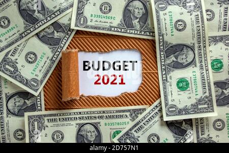 Geschäftskonzept der Planung 2021. Der Text "Haushalt 2021" erscheint hinter zerrissenem braunem Papier. Dollarscheine. Stockfoto
