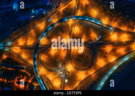 Straßenkreuzung, Brücken, Autobahnen und Autoverkehr in unscharfer Bewegung, Luftaufnahme bei Nacht. Stockfoto