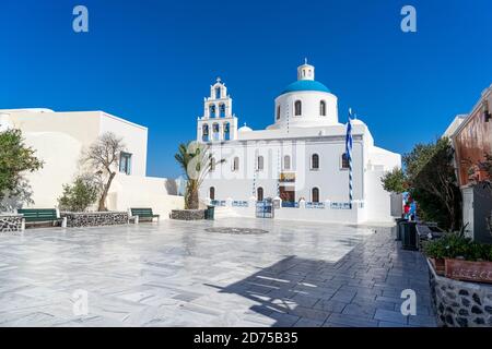 Orthodoxe Kirche in Oia, Santorini, Griechenland an einem Sommertag mit griechischer Flagge. Schöner klarer blauer Himmel. Stockfoto