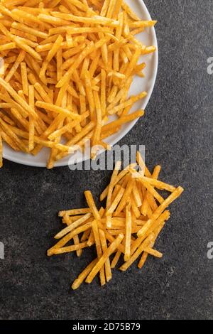 Pommes frites. Gebratene Mini-Kartoffelstäbchen auf schwarzem Tisch. Draufsicht. Stockfoto
